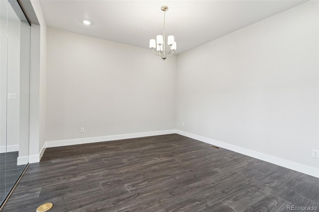 spare room with an inviting chandelier and dark wood-type flooring