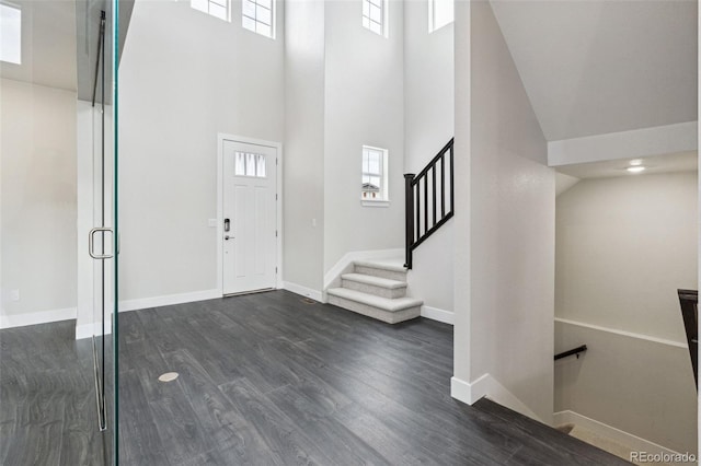 foyer entrance with a wealth of natural light, dark hardwood / wood-style flooring, and a towering ceiling