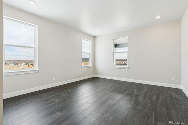 spare room featuring a wealth of natural light and dark hardwood / wood-style floors