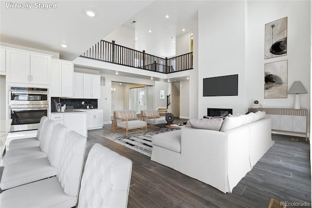 5566 Hickory Oaks Trl, Castle Rock, CO 80104 - living room featuring dark wood-style floors, a glass covered fireplace, recessed lighting, and a towering ceiling
