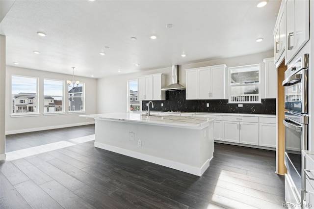 5566 Hickory Oaks Trl, Castle Rock, CO 80104 - kitchen with wall chimney range hood, stainless steel double oven, a chandelier, a sink, and decorative backsplash