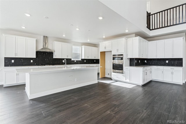 5566 Hickory Oaks Trl, Castle Rock, CO 80104 - kitchen with wall chimney range hood, double oven, decorative backsplash, a sink, and a center island with sink
