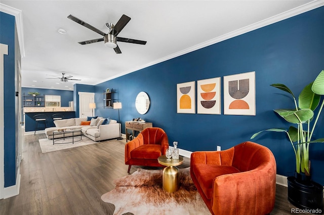 living room with a ceiling fan, wood finished floors, baseboards, and ornamental molding