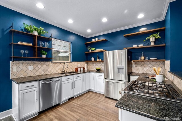 kitchen with light wood-type flooring, open shelves, a sink, stainless steel appliances, and crown molding