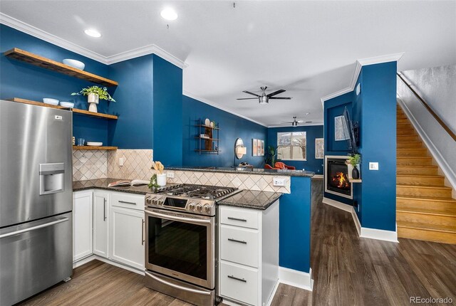 kitchen featuring a glass covered fireplace, appliances with stainless steel finishes, a peninsula, and dark wood-style flooring