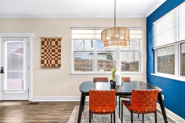 dining space featuring baseboards, wood finished floors, and crown molding