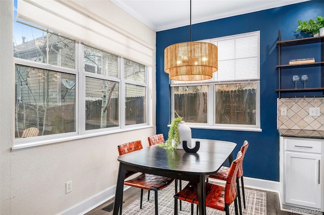 dining space with crown molding, wood finished floors, and baseboards