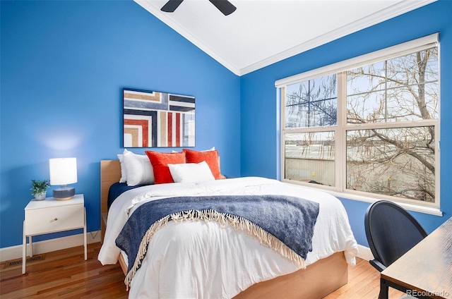 bedroom featuring lofted ceiling, wood finished floors, baseboards, and ornamental molding