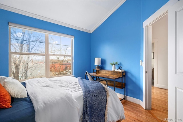 bedroom featuring baseboards, multiple windows, wood finished floors, and crown molding