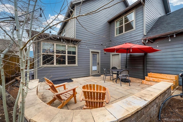 back of property featuring outdoor dining area, a patio, fence, and a shingled roof