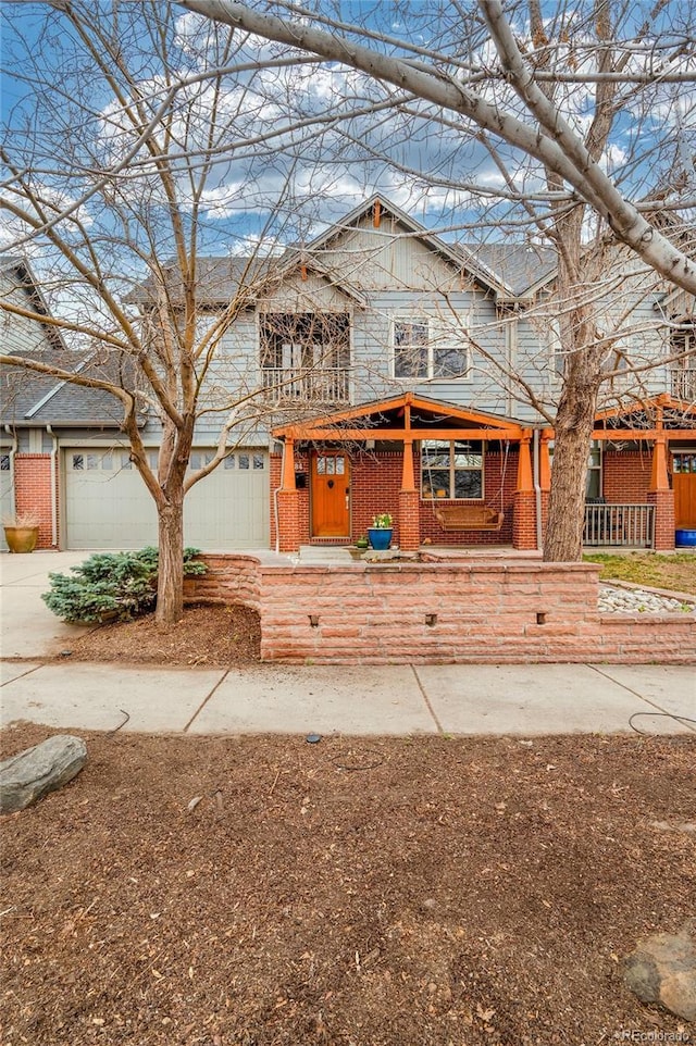 view of front of house featuring a garage, concrete driveway, a porch, and brick siding