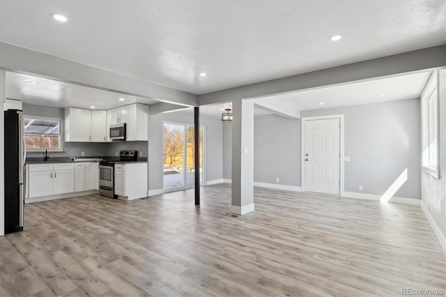 kitchen with appliances with stainless steel finishes, light wood-type flooring, and white cabinets