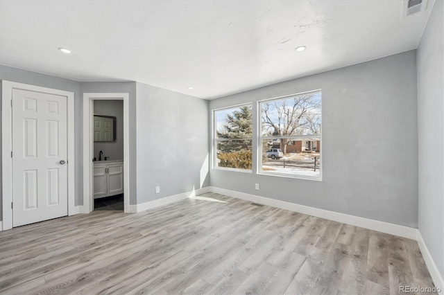 unfurnished bedroom featuring ensuite bath and light hardwood / wood-style flooring