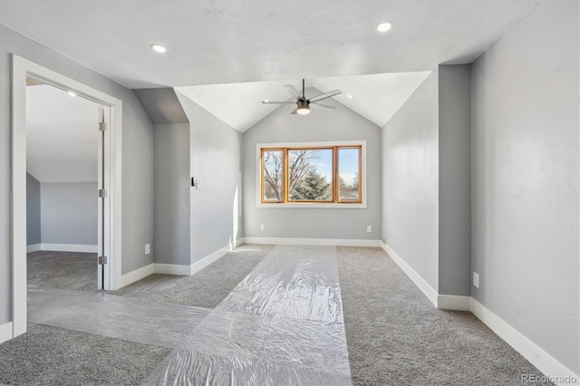 spare room featuring light carpet, vaulted ceiling, and ceiling fan