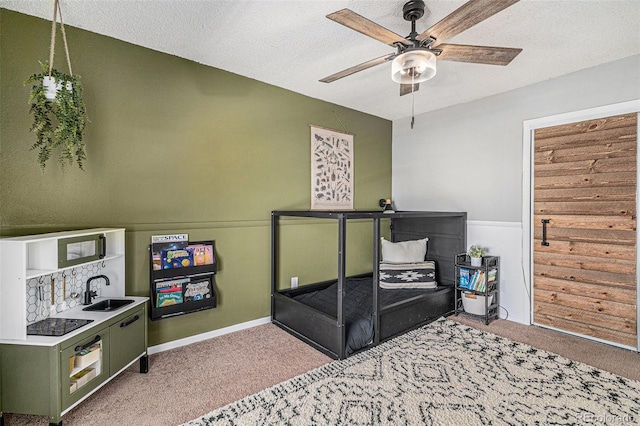 bedroom featuring ceiling fan, sink, light colored carpet, and a textured ceiling