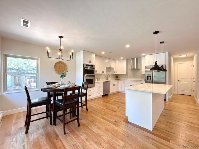 9451 E Evans Pl, Denver, CO 80231 - kitchen featuring wall chimney range hood, appliances with stainless steel finishes, light countertops, light wood-style flooring, and recessed lighting