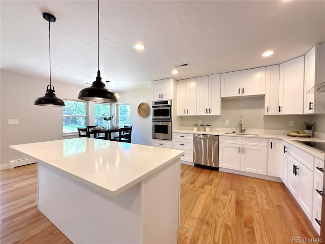 9451 E Evans Pl, Denver, CO 80231 - kitchen featuring stainless steel appliances, light wood-style flooring, light countertops, white cabinets, and a center island