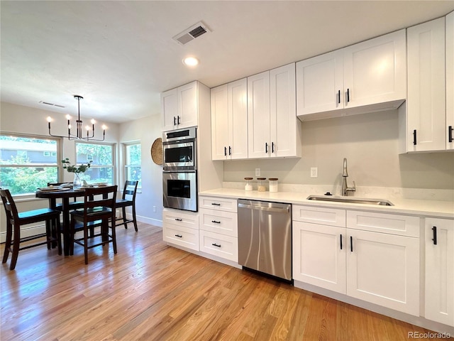 9451 E Evans Pl, Denver, CO 80231 - kitchen featuring appliances with stainless steel finishes, light countertops, light wood-style flooring, white cabinetry, and recessed lighting