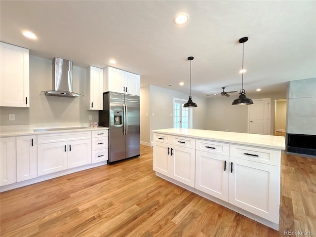 9451 E Evans Pl, Denver, CO 80231 - kitchen featuring stainless steel refrigerator with ice dispenser, wall chimney exhaust hood, black electric stovetop, light countertops, and light wood-style floors