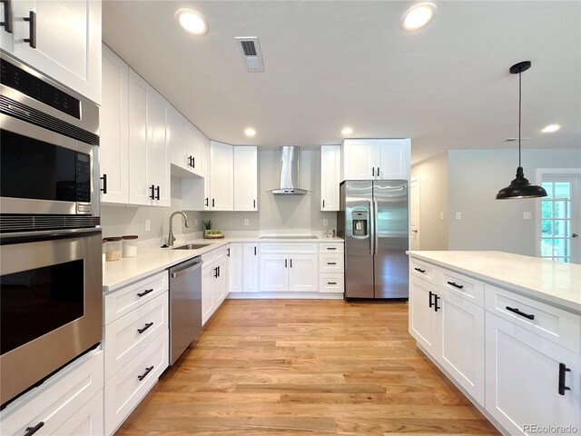 9451 E Evans Pl, Denver, CO 80231 - kitchen featuring appliances with stainless steel finishes, wall chimney range hood, white cabinetry, light countertops, and recessed lighting