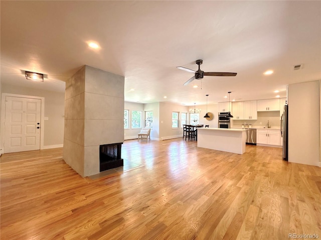 9451 E Evans Pl, Denver, CO 80231 - unfurnished living room featuring light wood-style flooring, recessed lighting, a ceiling fan, and a fireplace