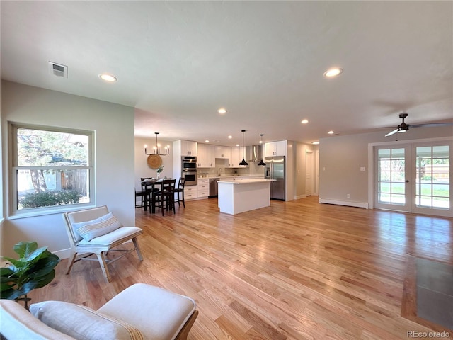 9451 E Evans Pl, Denver, CO 80231 - living room with baseboard heating, light wood-type flooring, recessed lighting, a ceiling fan, and a chandelier