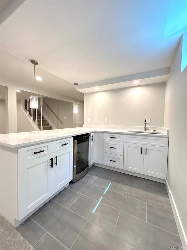 9451 E Evans Pl, Denver, CO 80231 - kitchen with a peninsula, wine cooler, white cabinetry, hanging light fixtures, and light countertops