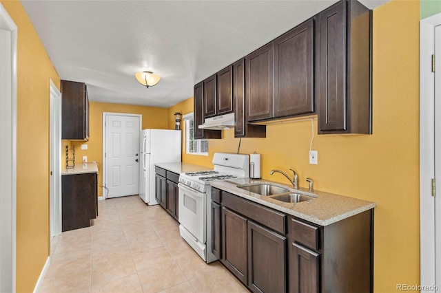 kitchen with dark brown cabinetry, sink, light tile patterned floors, and white appliances