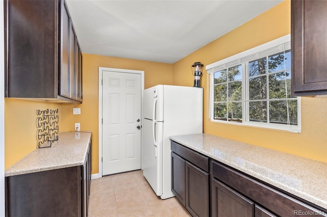 kitchen featuring dark brown cabinets, light tile patterned floors, and white refrigerator