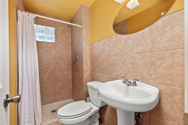 bathroom featuring a shower with curtain, toilet, and tile walls