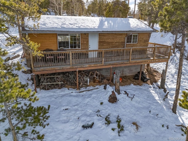 snow covered rear of property with a deck