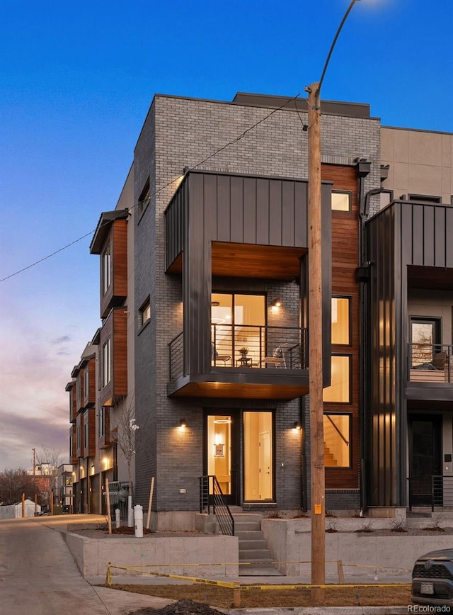 back of property with brick siding and a balcony