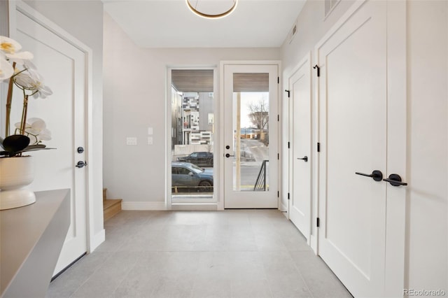 doorway to outside featuring light tile patterned flooring, visible vents, and baseboards