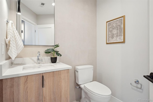 half bath with visible vents, vanity, and toilet