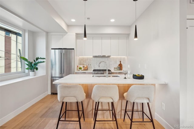 kitchen featuring high end fridge, a sink, a kitchen breakfast bar, and modern cabinets