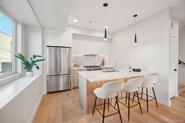 kitchen featuring modern cabinets, a breakfast bar, freestanding refrigerator, a peninsula, and a sink