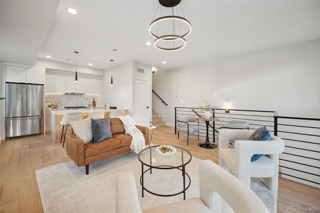 living area with light wood-style flooring, stairs, a chandelier, and recessed lighting