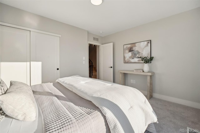 carpeted bedroom with a closet, visible vents, and baseboards