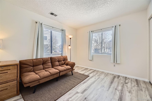 living room featuring plenty of natural light, light hardwood / wood-style floors, and a textured ceiling