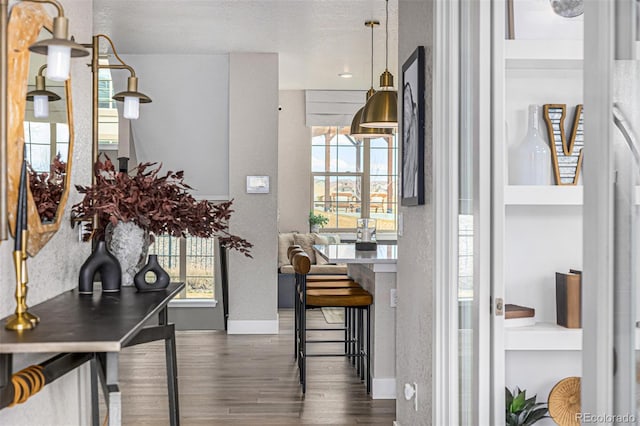 interior space featuring baseboards, a textured ceiling, wood finished floors, and a healthy amount of sunlight