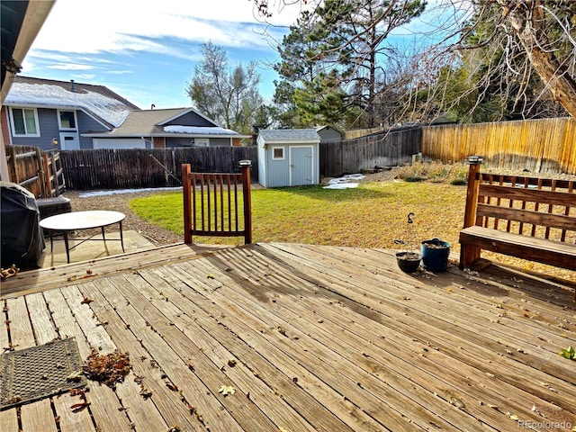 deck featuring a lawn, grilling area, and a storage unit