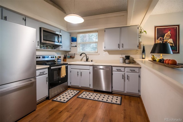 3300 W Florida Ave Unit 37, Denver, CO 80219 - kitchen with appliances with stainless steel finishes, wood finished floors, light countertops, a textured ceiling, and gray cabinetry