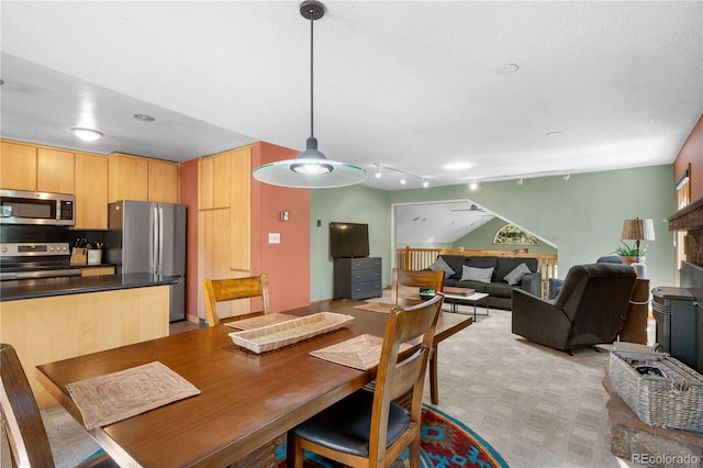 dining area featuring light carpet, track lighting, and a textured ceiling