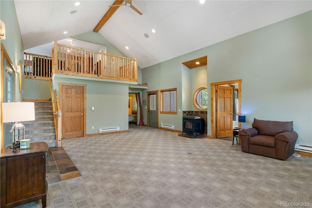 living area with stairway, a wood stove, high vaulted ceiling, carpet floors, and a baseboard heating unit