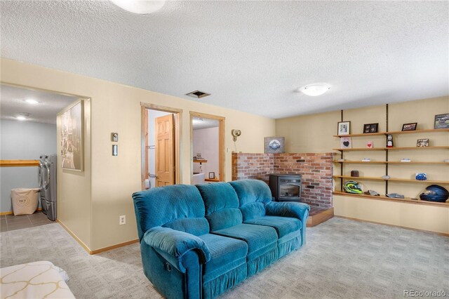 living area featuring a wood stove, light carpet, a textured ceiling, and baseboards