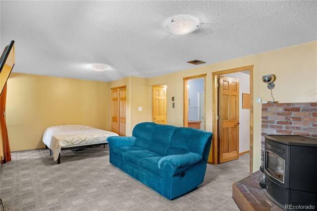 interior space with light carpet, a wood stove, visible vents, and a textured ceiling