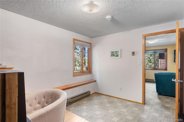 sitting room featuring a baseboard radiator, baseboards, and a textured ceiling