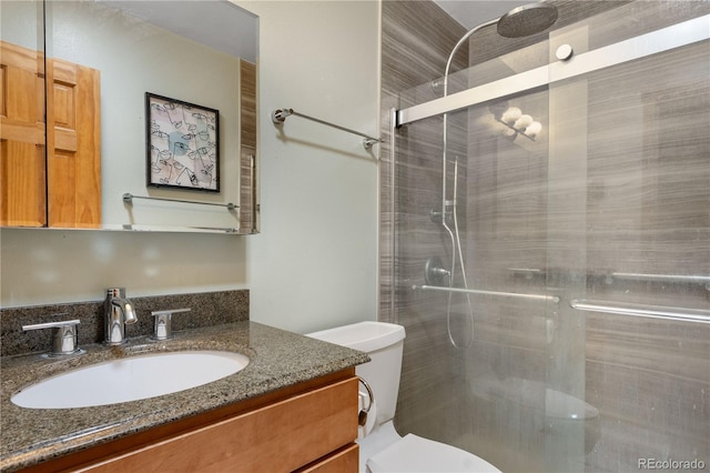 full bathroom featuring vanity, a tile shower, and toilet