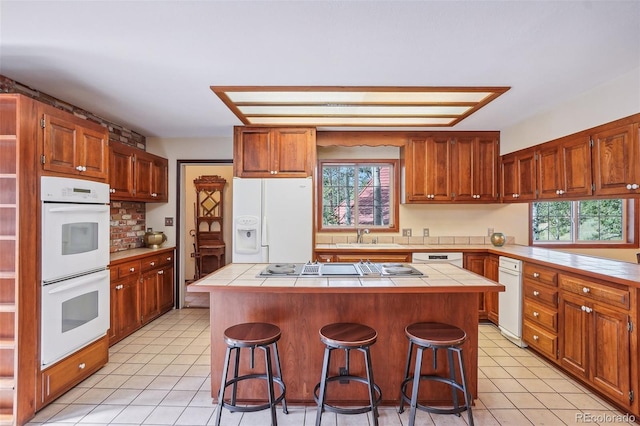 kitchen featuring plenty of natural light, a center island, tile countertops, and white appliances