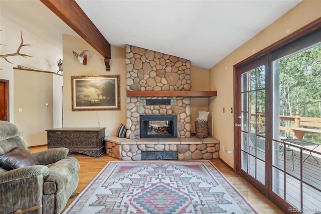 living room featuring light hardwood / wood-style flooring, a stone fireplace, and lofted ceiling with beams